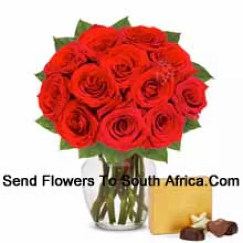 12 roses rouges avec des fougères dans un vase en verre accompagnées d'une boîte de chocolats importée
