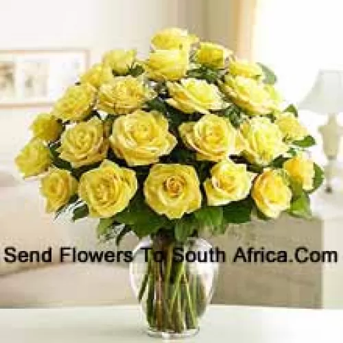 24 Yellow Roses With Some Ferns In A Glass Vase