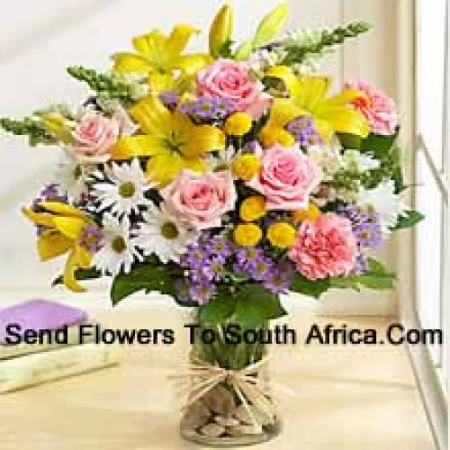 Roses roses, Oeillets roses, Géraniums blancs et Lys jaunes avec des remplissages saisonniers dans un vase en verre